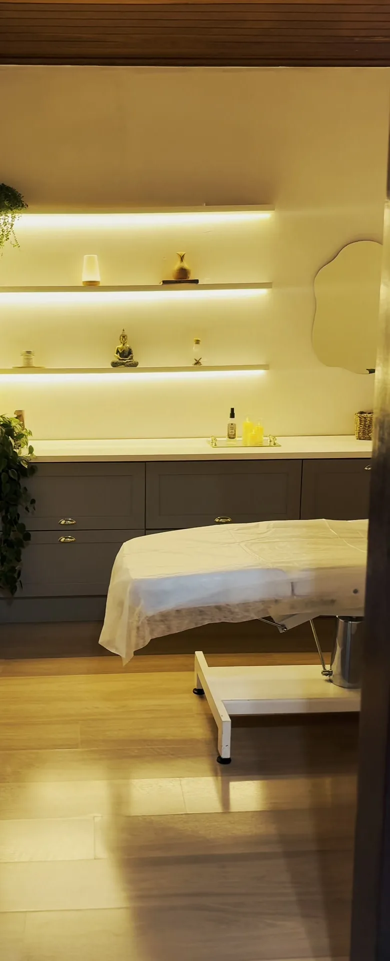 Sala individual de massoterapia da GÜVEN, com maca preparada e nichos iluminados.